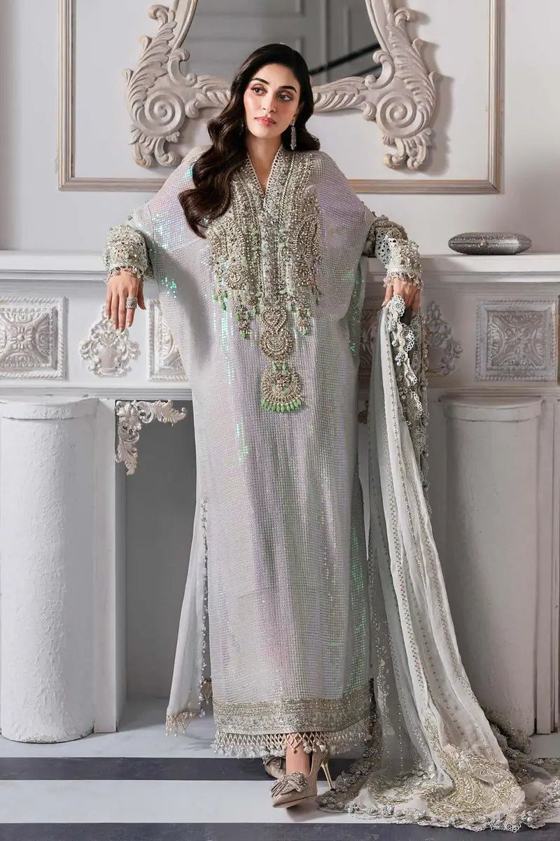 Woman in a traditional embroidered outfit standing in a decorative interior setting.