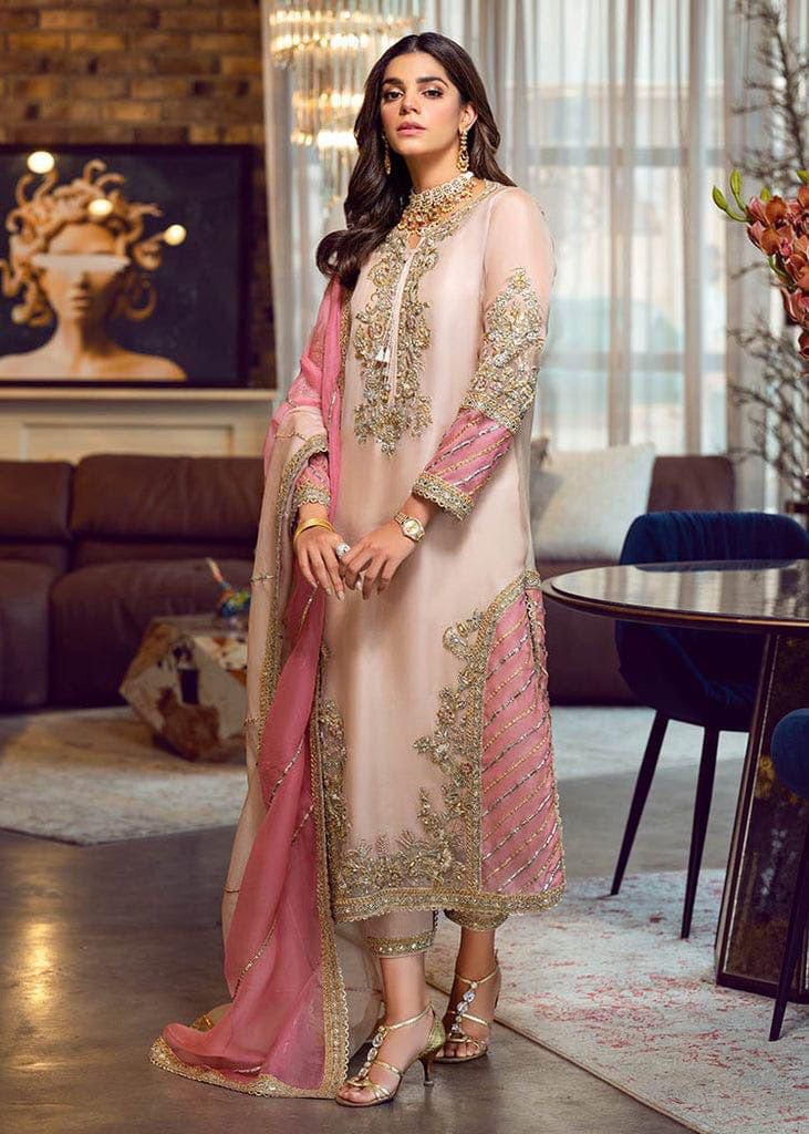 A woman wearing a pink and gold Agha Noor organza dress with thread and handwork, consisting of a shirt and malai trouser.