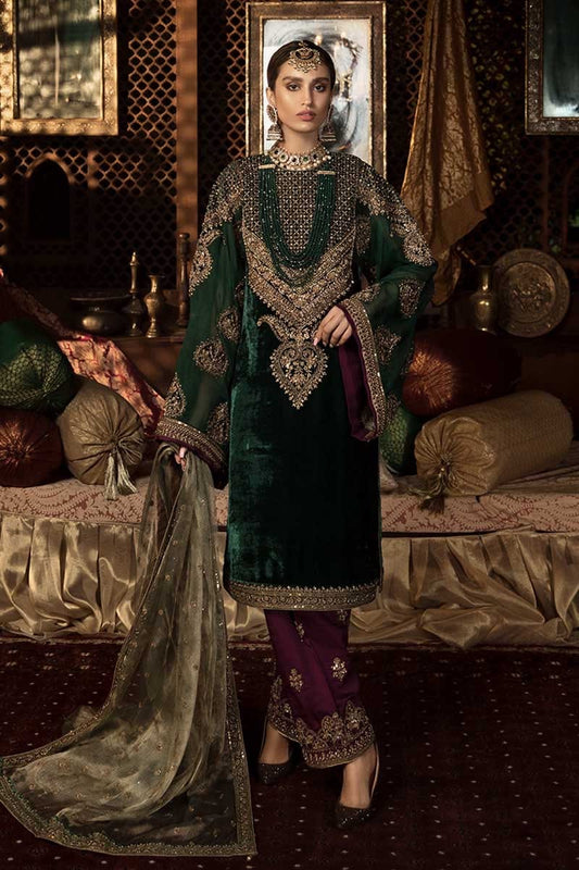 Woman in traditional green and purple outfit with intricate patterns in a decorated room.