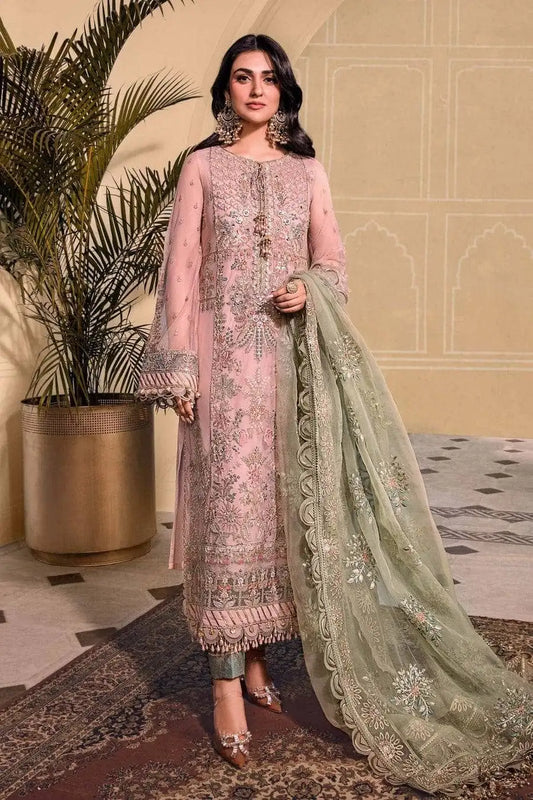 Woman in a pink embroidered outfit with a green dupatta standing indoors.