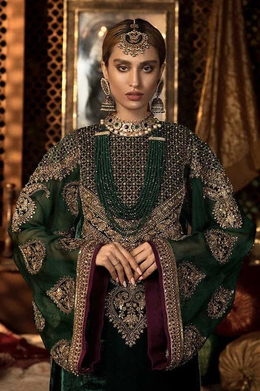 Woman in traditional green and black embroidered outfit with jewelry in a decorative setting
