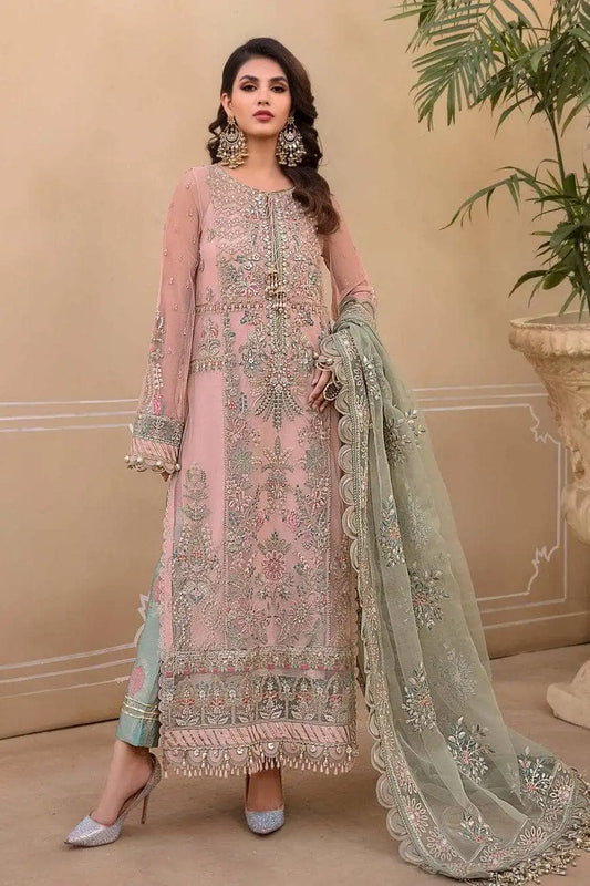 Woman in a pink embroidered outfit with a green dupatta in an indoor setting.