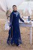 Woman in a blue embroidered outfit standing in a desert setting with a decorated table.