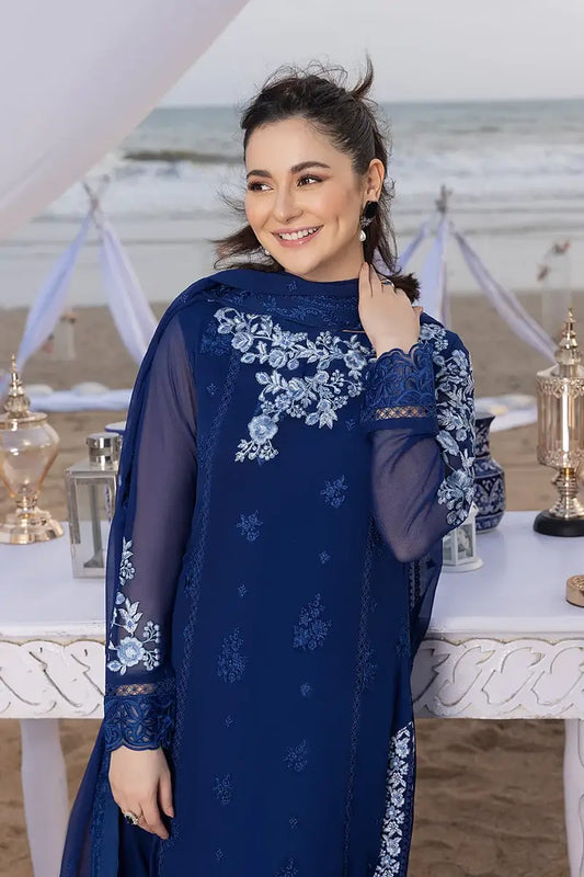 Woman wearing a blue embroidered dress at an event with trophies in the background