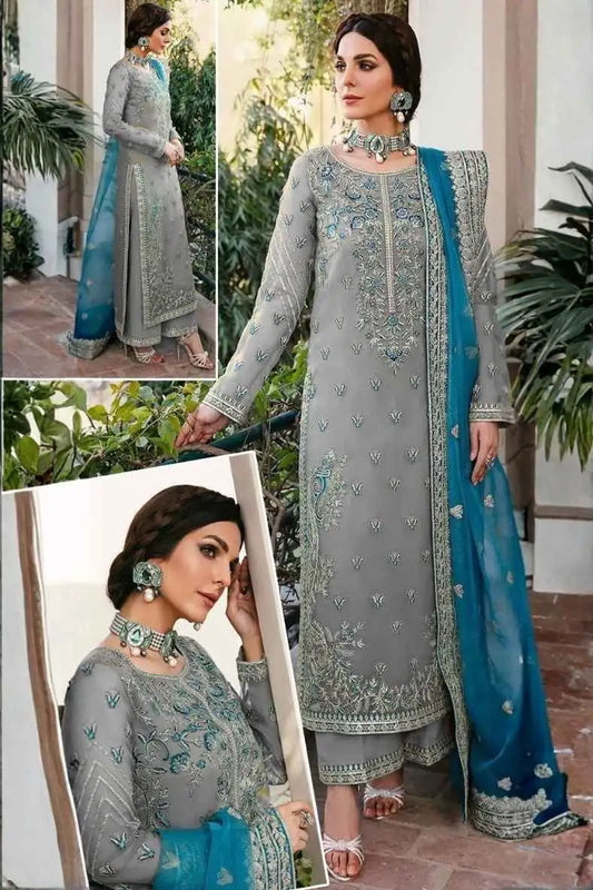 Woman wearing a gray and blue embroidered traditional outfit with plants in the background