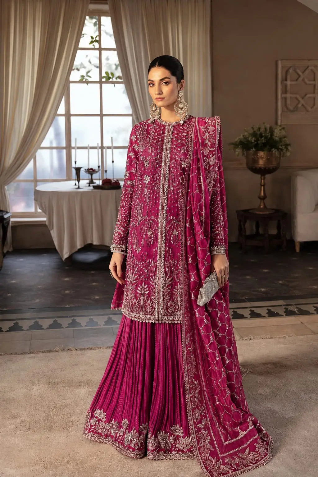 Woman posing in a Hotpink organza 3-piece formal suit featuring a heavily silver-embroidered straight shirt, pleated flared sharara bottoms, and an embroidered organza dupatta.
