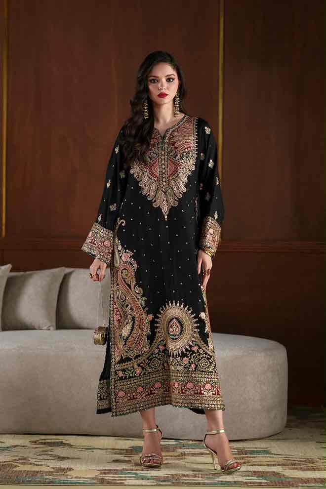 Full-length front view of model wearing a black shamoz silk kaftan by Ethnic with rich gold and pink embroidery paired with metallic high heels. Shop now!