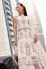 Woman wearing a white lace dress standing in an urban setting with tall buildings.