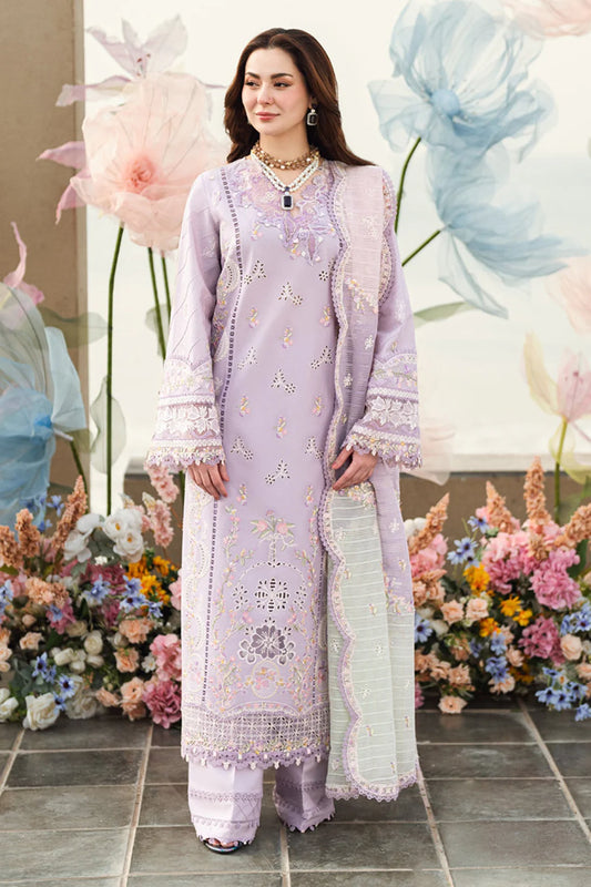 Woman in a light purple embroidered outfit standing in front of floral decorations.